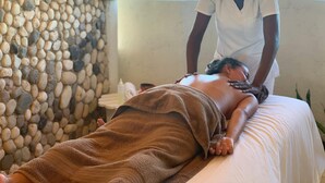 A massage therapy session in a room with a stone wall and a view of the ocean. - Franklyn D. Resort & Spa (Runaway Bay)
