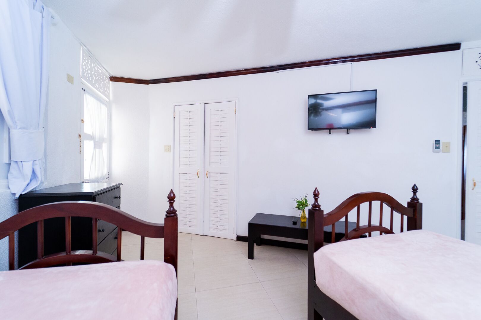 Una habitación de hotel con dos camas, un televisor en la pared, un escritorio y un armario.