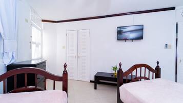 Una habitación de hotel con dos camas, un televisor en la pared, un escritorio y un armario.