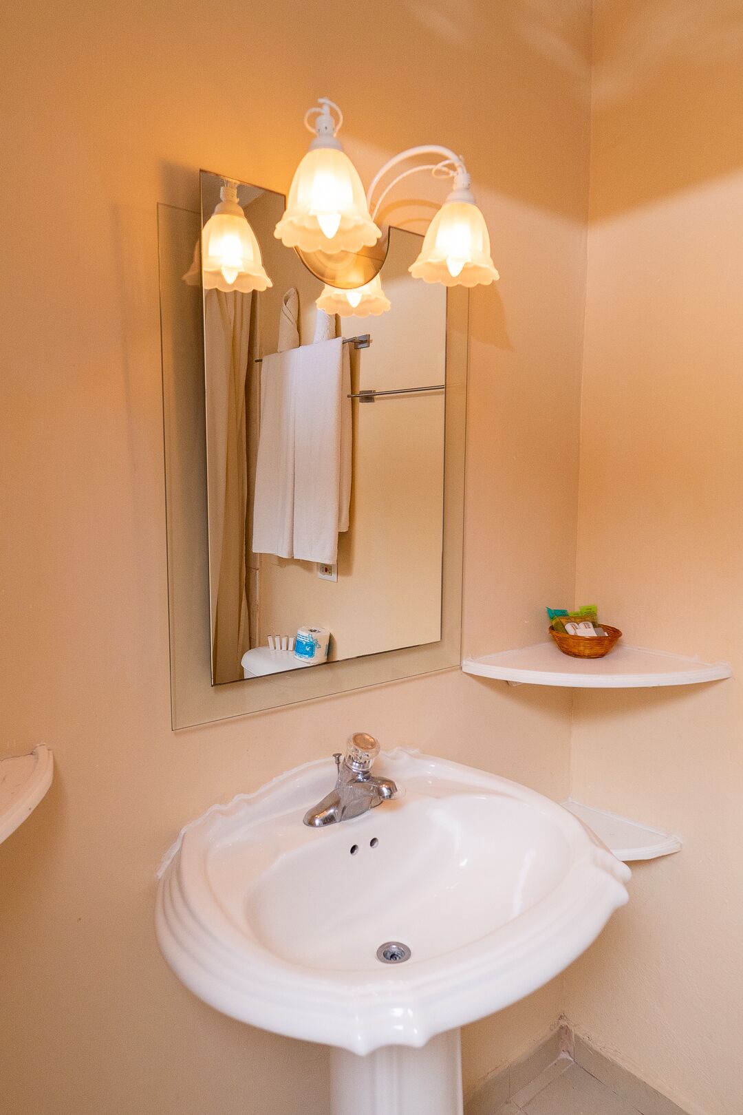 A bathroom with a white sink, a mirror, and a wall-mounted light fixture.