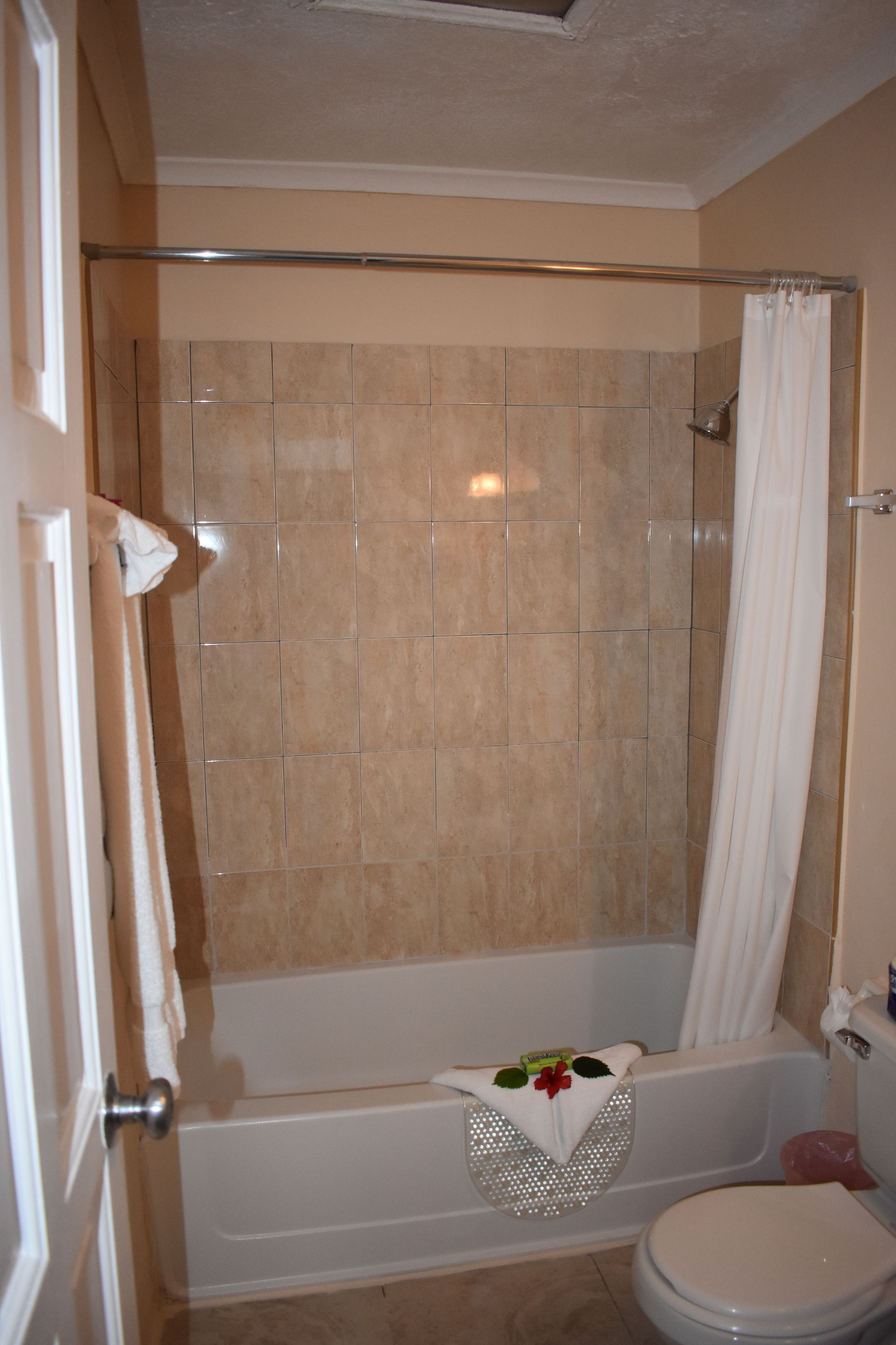 Een badkamer met een bad, douchegordijn en toilet.