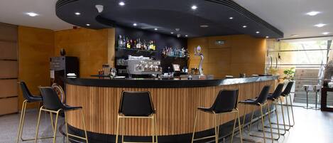 Un área de bar moderna con una barra curva, taburetes y una estantería bien surtida con varias botellas.