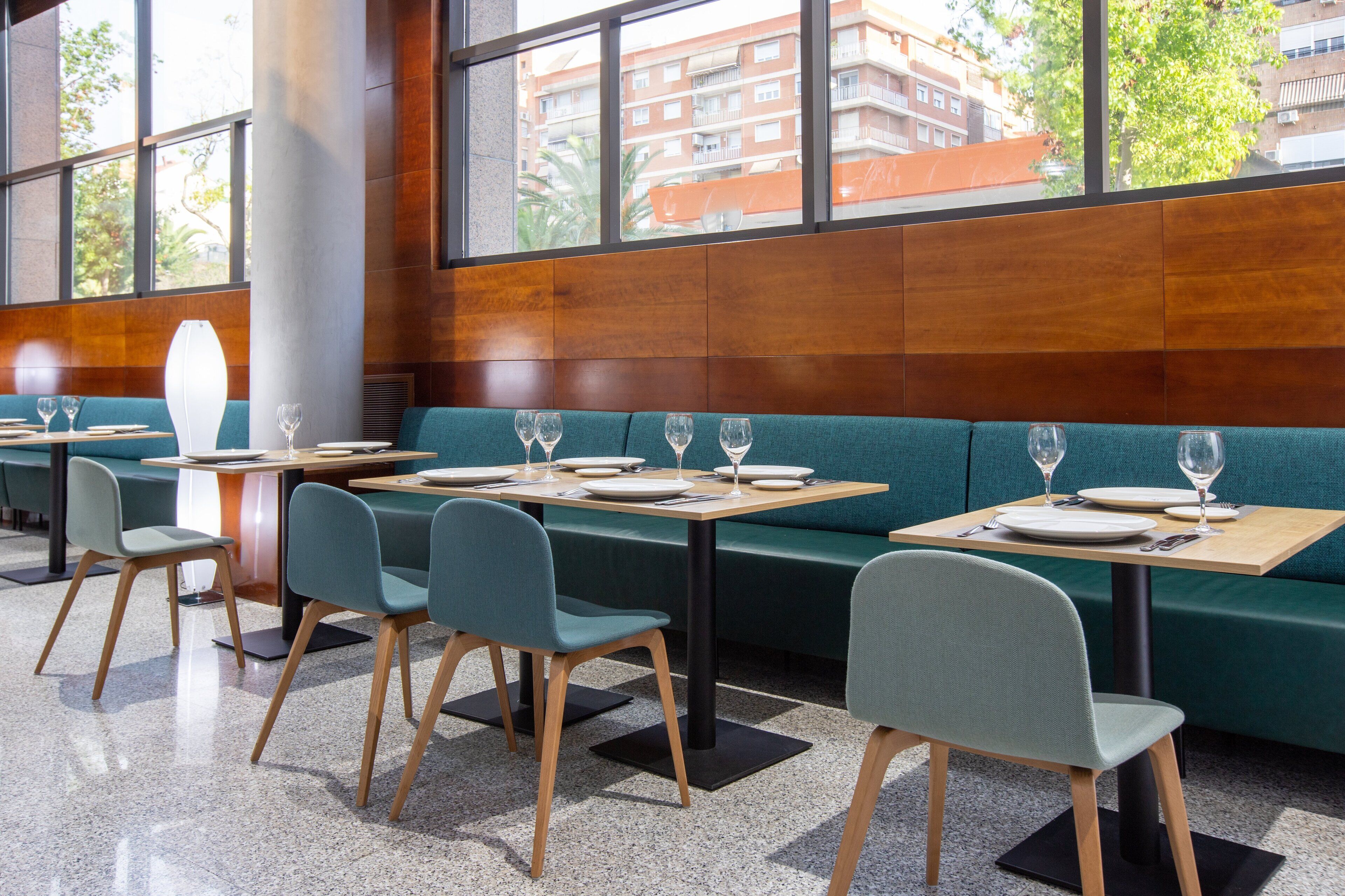 Un restaurante moderno con cabinas tapizadas de verde, mesas y sillas de madera.
