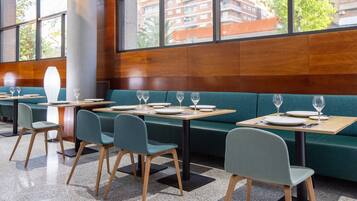 Un restaurante moderno con cabinas tapizadas de verde, mesas y sillas de madera.