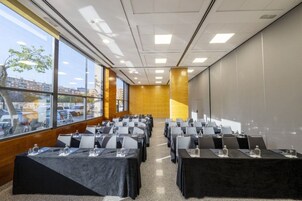 A conference room with rows of tables, large windows, and a view of the cityscape.