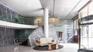A lobby with a marble reception desk, a sofa, and a staircase. - Hotel Eurostars Acteón (Valencia)