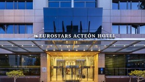 The entrance of the Eurostars Actéon Hotel with a glass facade, a covered entrance area, and potted plants. - Hotel Eurostars Acteón (Valencia)