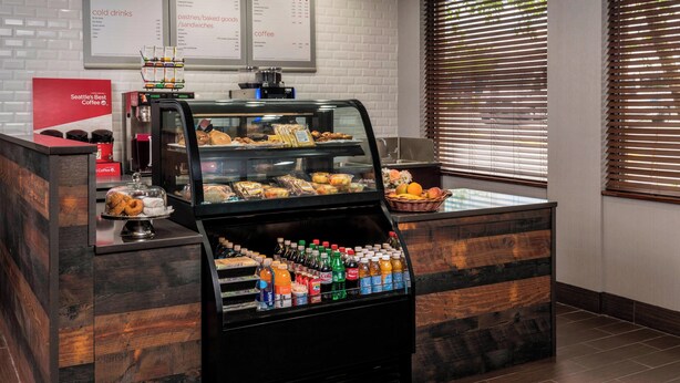 Una estación de café con una vitrina de pasteles y un dispensador de bebidas.