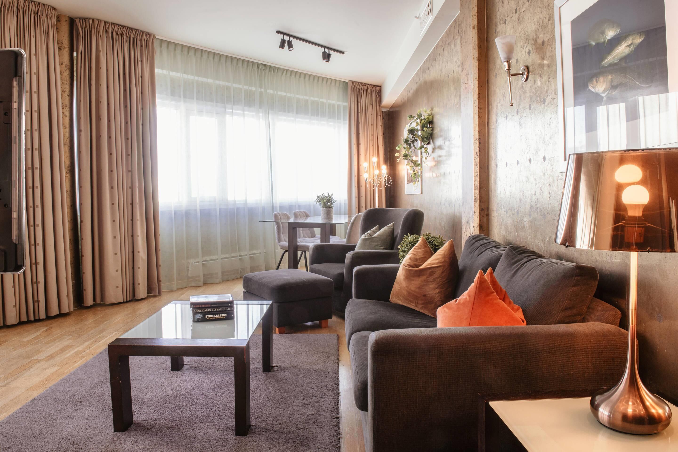 A modern living room with a sofa, ottoman, coffee table, and a lamp.