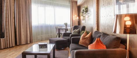 A modern living room with a sofa, ottoman, coffee table, and a lamp.