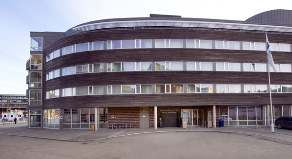 A modern hotel with a curved facade, large windows, and a visible entrance with a sign for the Clarion Collection Hotel Aurora.