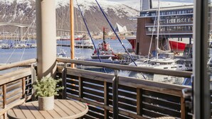 Un balcone con vista su una marina, imbarcazioni e un ponte sullo sfondo.