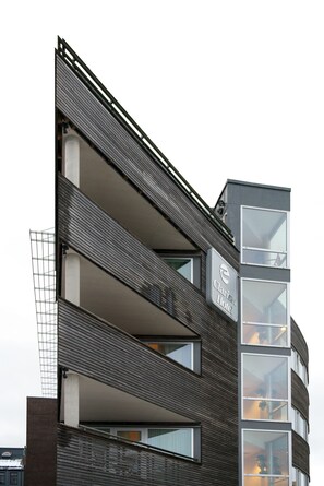 A modern hotel with a dark facade, multiple balconies, and large windows. - Home Hotel Aurora (Tromsø)