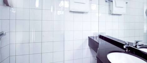 A modern bathroom with white tiles, a black sink, and a glass shower enclosure.