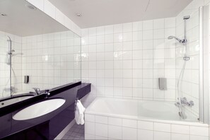 A modern bathroom with a large mirror, a black countertop, a white sink, and a glass-enclosed shower area. - Home Hotel Aurora (Tromsø)