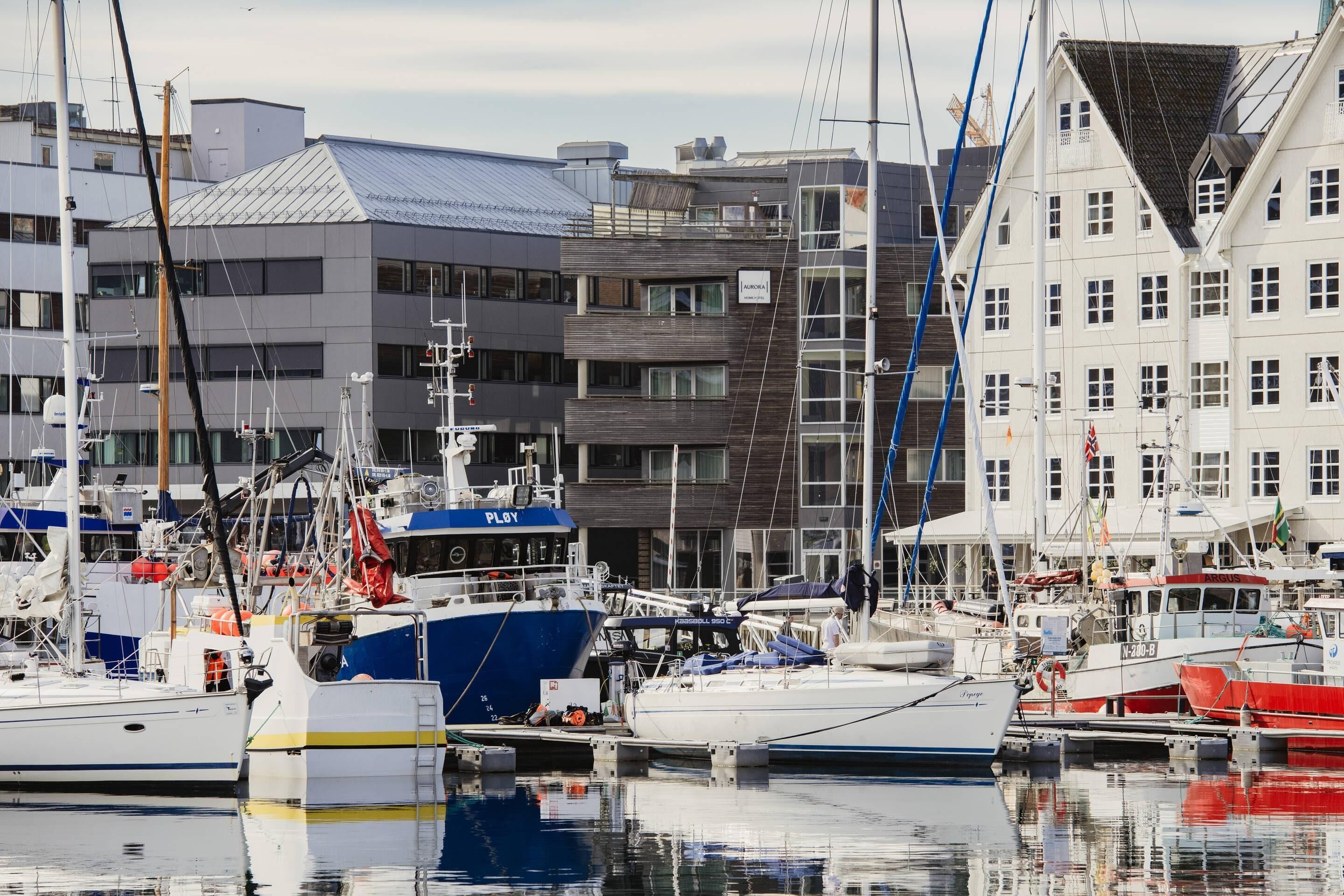 Een jachthaven met aan wal liggende boten, gebouwen met balkons, en een heldere lucht.