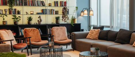 Una sala de estar moderna con un sofá, sillones, una mesa de centro, una estantería y una lámpara de pie.
