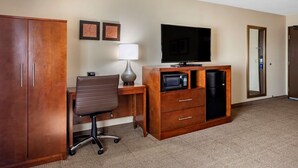 A hotel room with a wooden desk, a brown office chair, a flat-screen TV, a microwave, a lamp, and a wardrobe. - Comfort Inn Nashville West (Nashville)