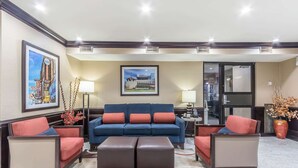 A lobby with a blue sofa, red chairs, a brown ottoman, and framed pictures on the walls. - Comfort Inn Nashville West (Nashville)