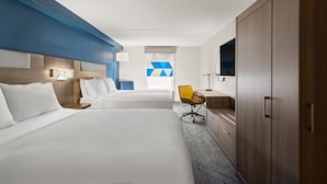 Una habitación de hotel con dos camas, un escritorio, una silla y un armario.