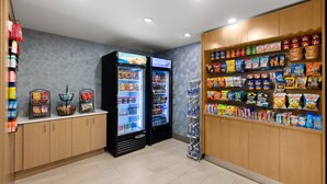 A self-service snack and beverage area with refrigerated drink dispensers and shelves stocked with various snacks and beverages. - Holiday Inn Express Hotel & Suites Danbury - I-84 by IHG (Danbury)