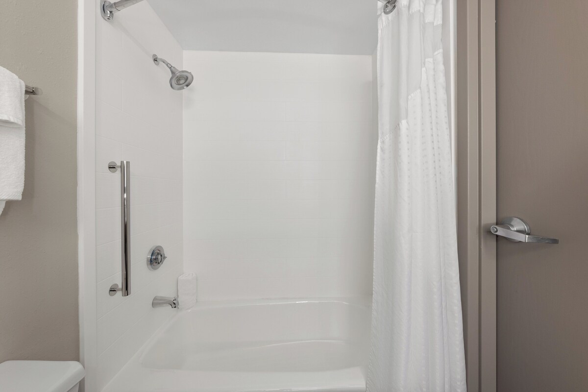 A bathroom with a shower, toilet, and bathtub.