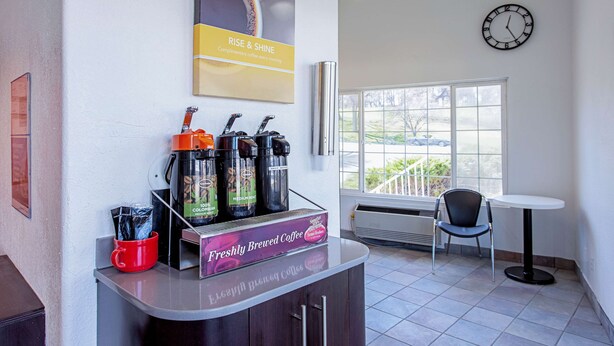 A coffee station with a coffee machine, cups, and a sign that says "Freshly Brewed Coffee." - Motel 6 Pendleton, OR - West (Pendleton)