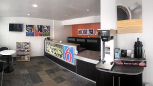 A reception area with a counter, a coffee machine, and a sign that reads "RISE & SHINE". - Motel 6 Pendleton, OR - West (Pendleton)