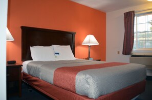 A hotel room with a large bed, two bedside tables, a lamp, and a window with curtains.