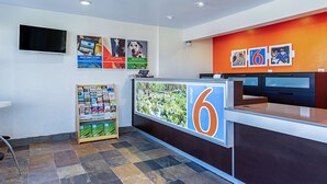 A reception area with a large '6' sign, a television mounted on the wall, and a bulletin board with various flyers. - Motel 6 Pendleton, OR - West (Pendleton)