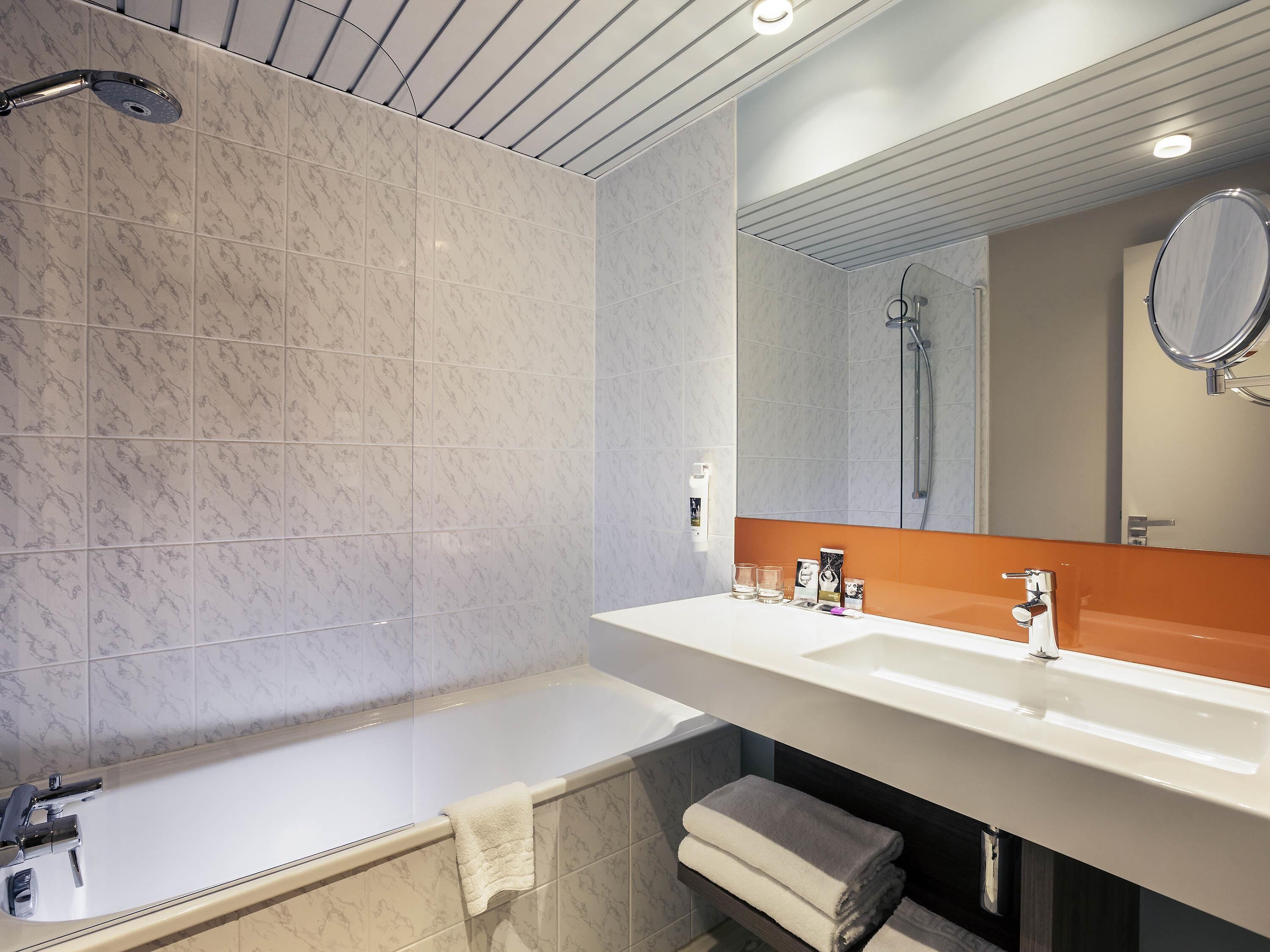 A modern bathroom with a bathtub, a large mirror, and a sink.