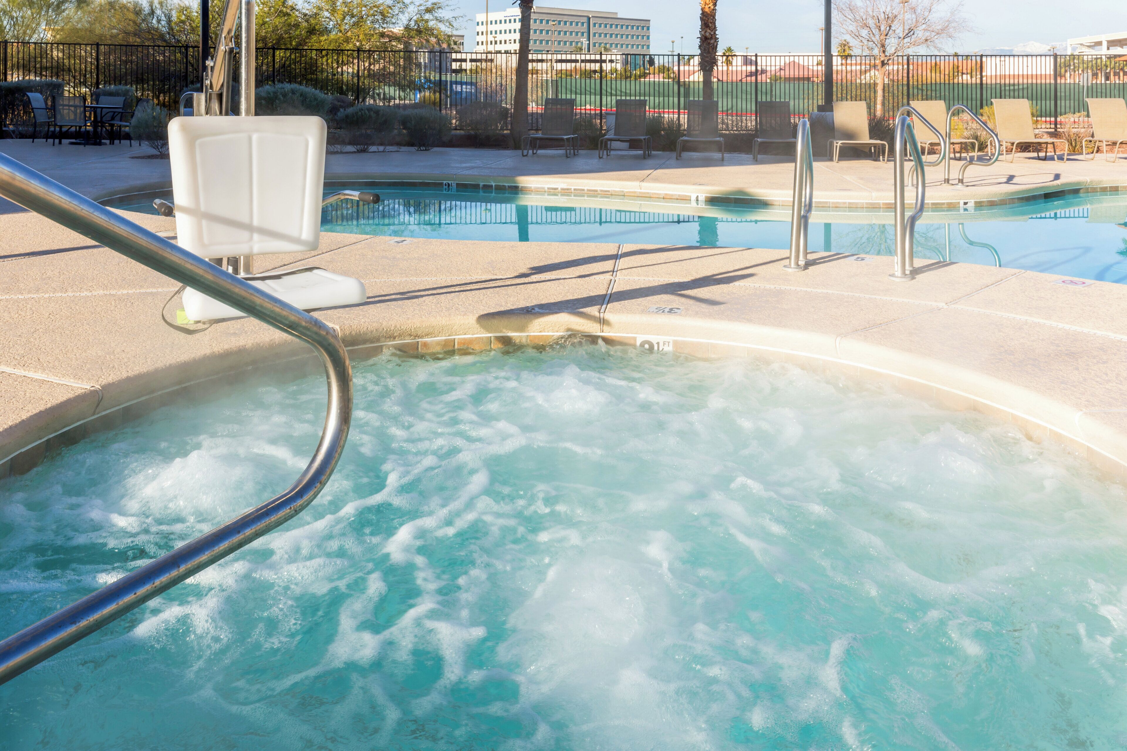 A hot tub area with a pool and lounge chairs.