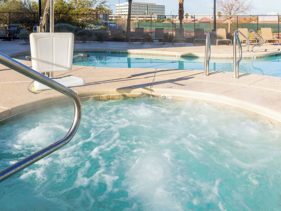A hot tub area with a pool and lounge chairs.