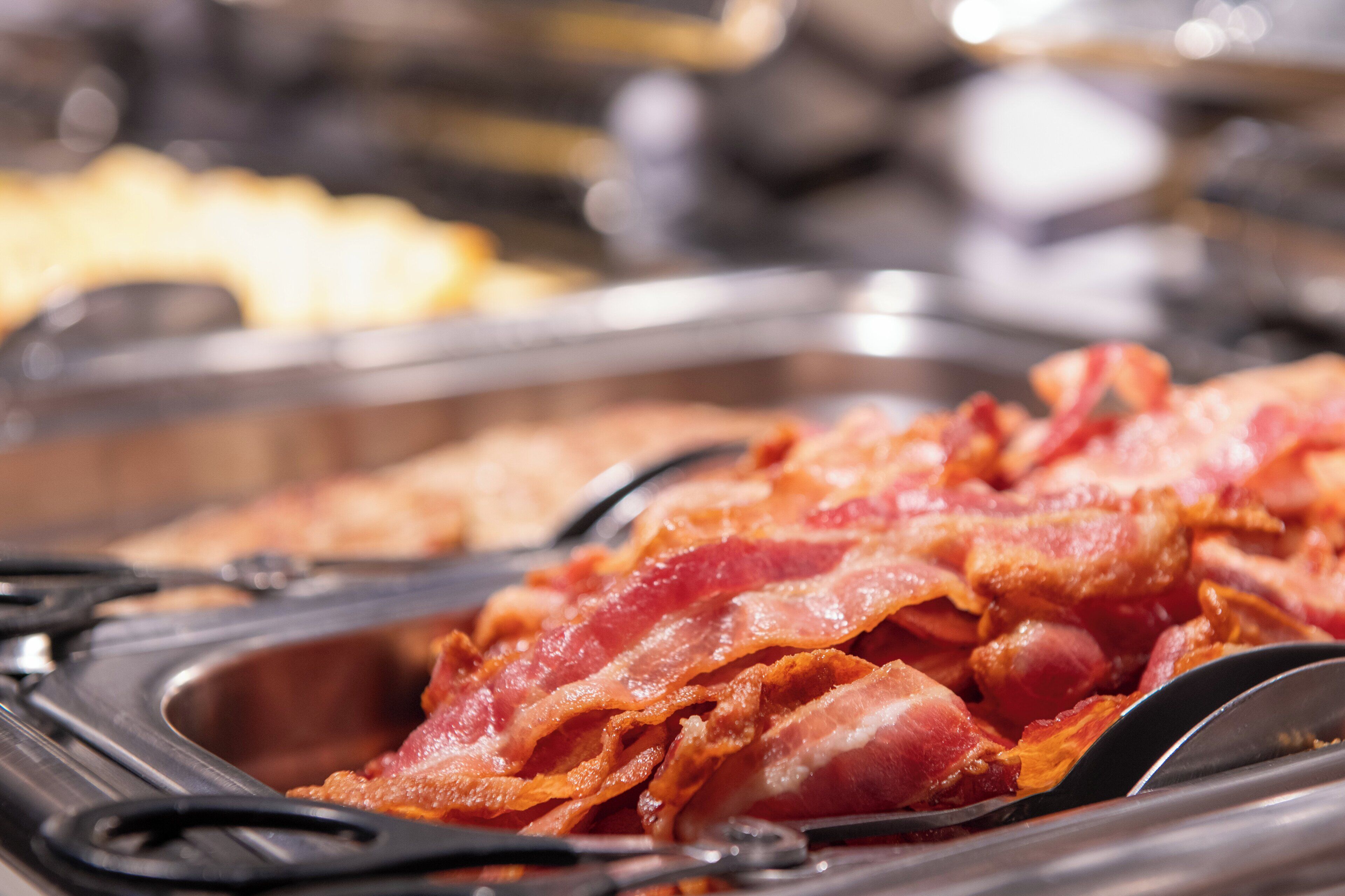 Un bufé con diversos alimentos, incluyendo tocino.