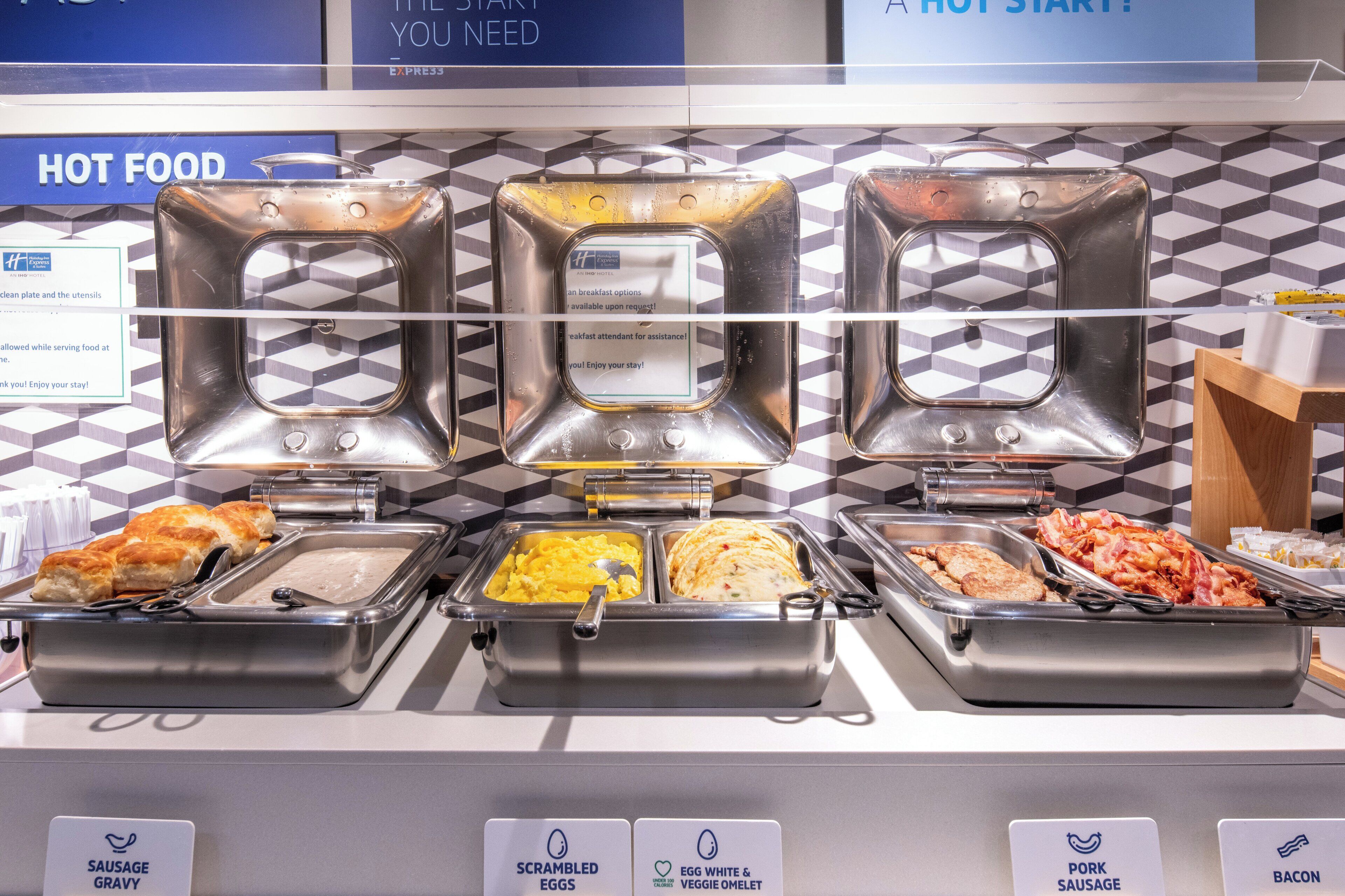 A buffet with labeled food options including sausage gravy, scrambled eggs, egg white and veggie omelet, pork sausage, and bacon.