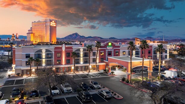 A hotel with a modern design, multiple floors, and a parking lot with several cars. - Holiday Inn Express Hotel & Suites Henderson by IHG (Henderson)