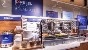 A buffet breakfast area with labeled sections for cereal, hot food, and a Quaker Oatmeal dispenser. - Holiday Inn Express Hotel & Suites Henderson by IHG (Henderson)