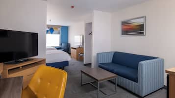 A hotel room with a bed, a TV, a sofa, a desk, and a chair.