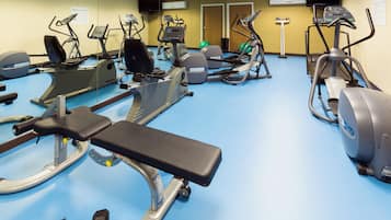 A fitness center with various exercise equipment including treadmills, elliptical machines, and a bench.