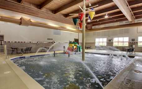 An indoor pool with water jets, a slide, and a no-drink sign.