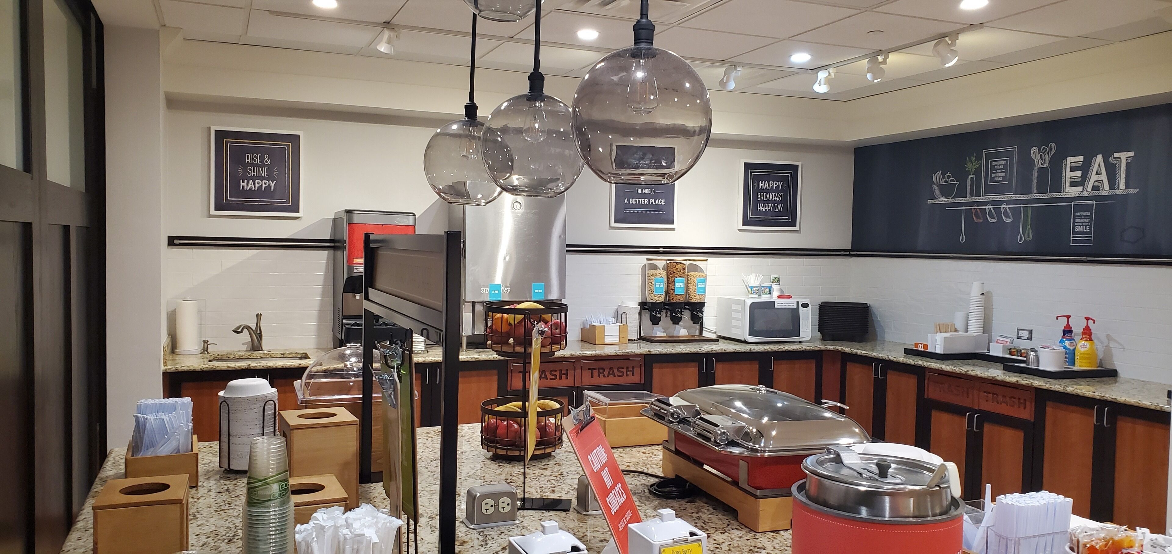 A breakfast area with a coffee machine, fruit baskets, and a microwave.