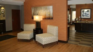 A hotel lobby with two armchairs, a lamp, a painting, and a checkered floor. - Hampton Inn Tulsa-Sand Springs (Tulsa)