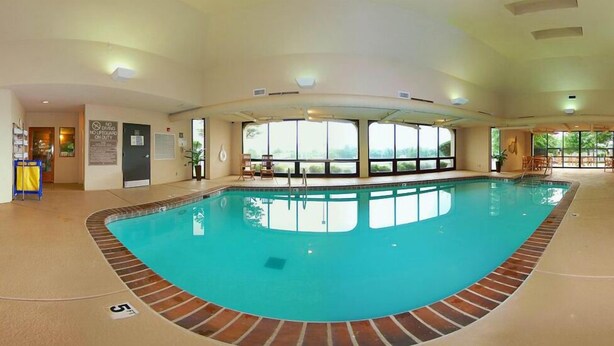 An indoor swimming pool with clear views of the outdoors through large windows, a lifeguard station, and a poolside seating area. - Hampton Inn Tulsa-Sand Springs (Tulsa)