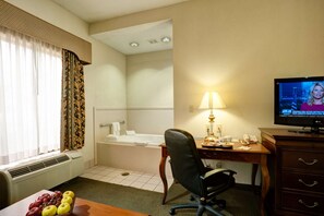 Ein Hotelzimmer mit Schreibtisch, Stuhl, Fernseher und einer Badewanne.