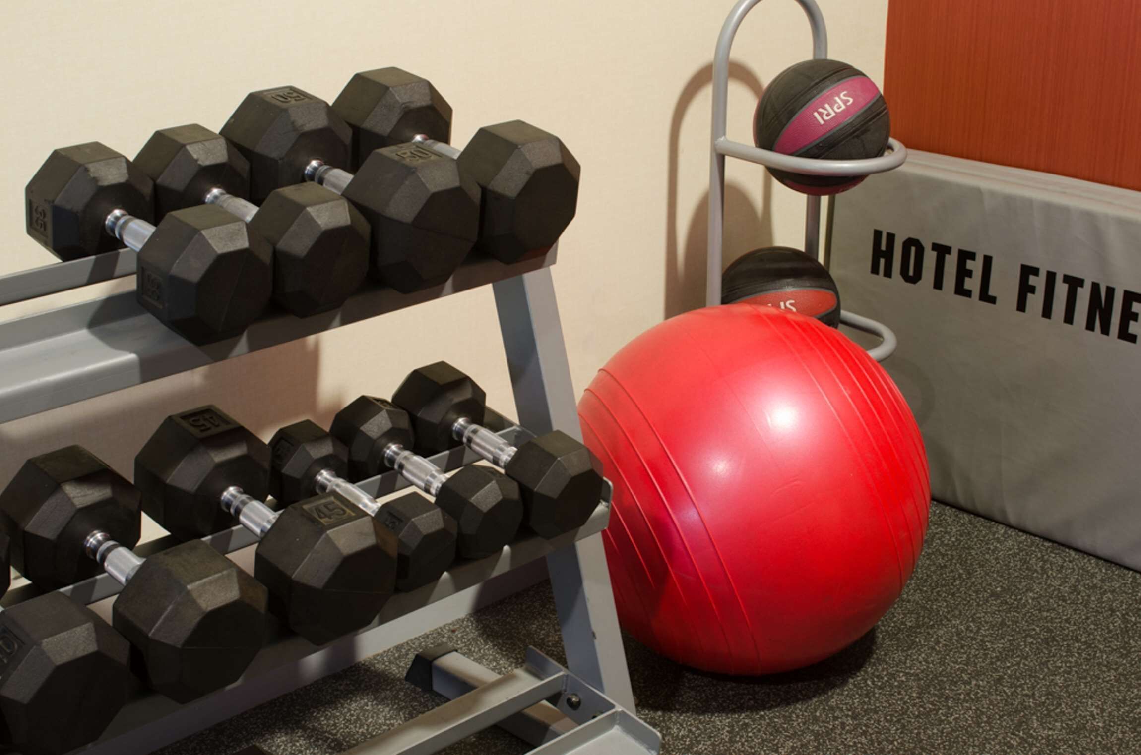 A hotel fitness area with dumbbells and a red exercise ball.