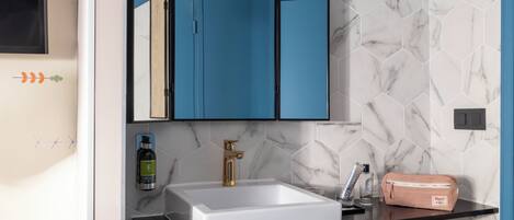 A bathroom with a white sink, a mirror, and a blue cabinet.