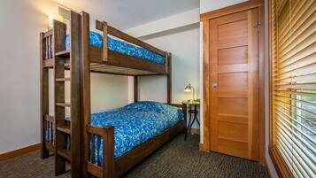 A bunk bed room with a wooden door and a small table with a lamp.