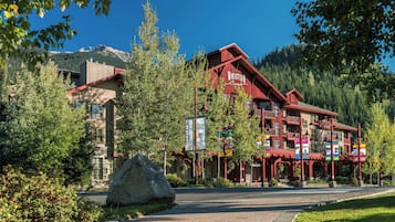 A red building with 'Whistler Creek' signage, surrounded by trees and a mountain backdrop.