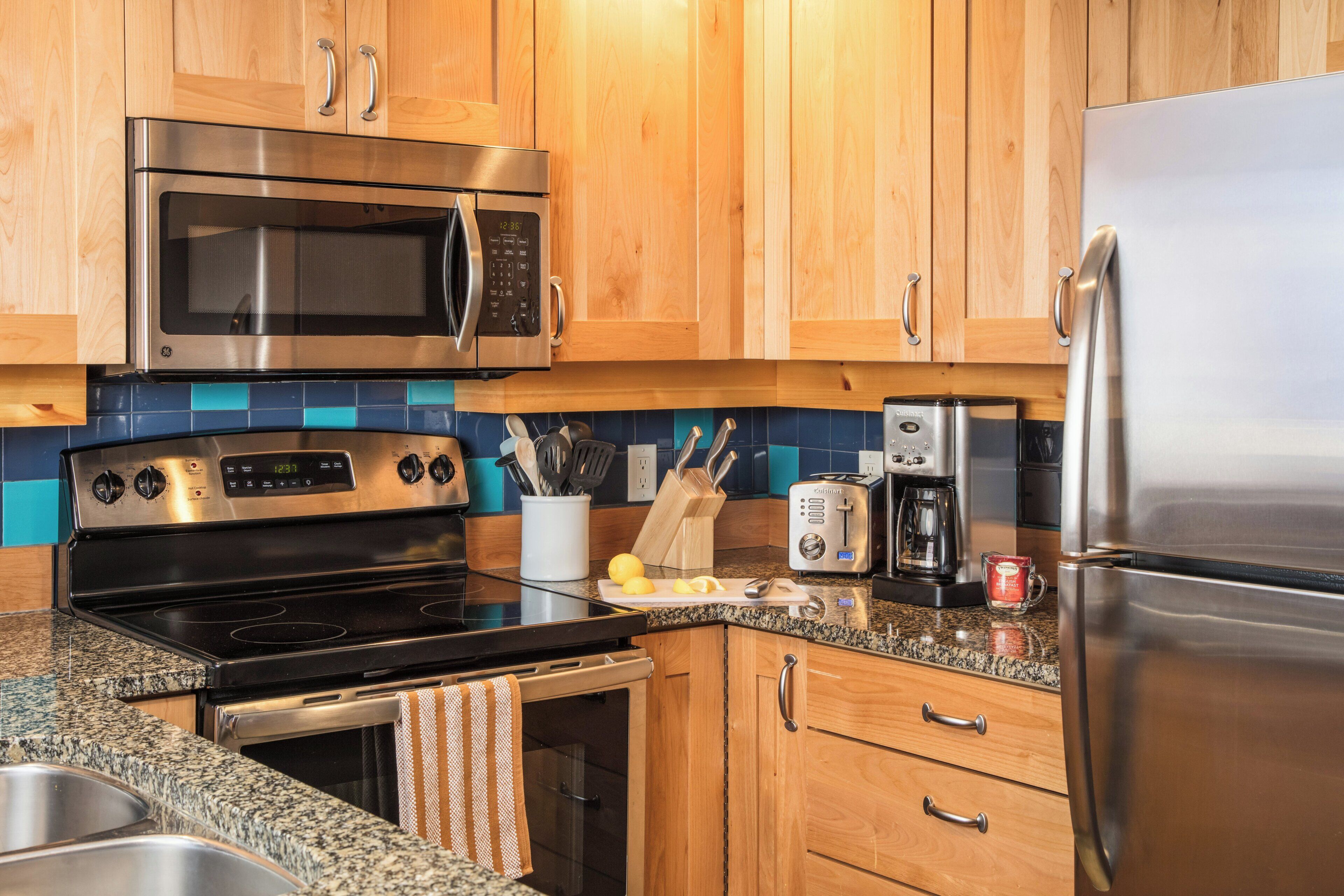 A kitchen with wooden cabinets, stainless steel appliances, a microwave, toaster, and a coffee maker.