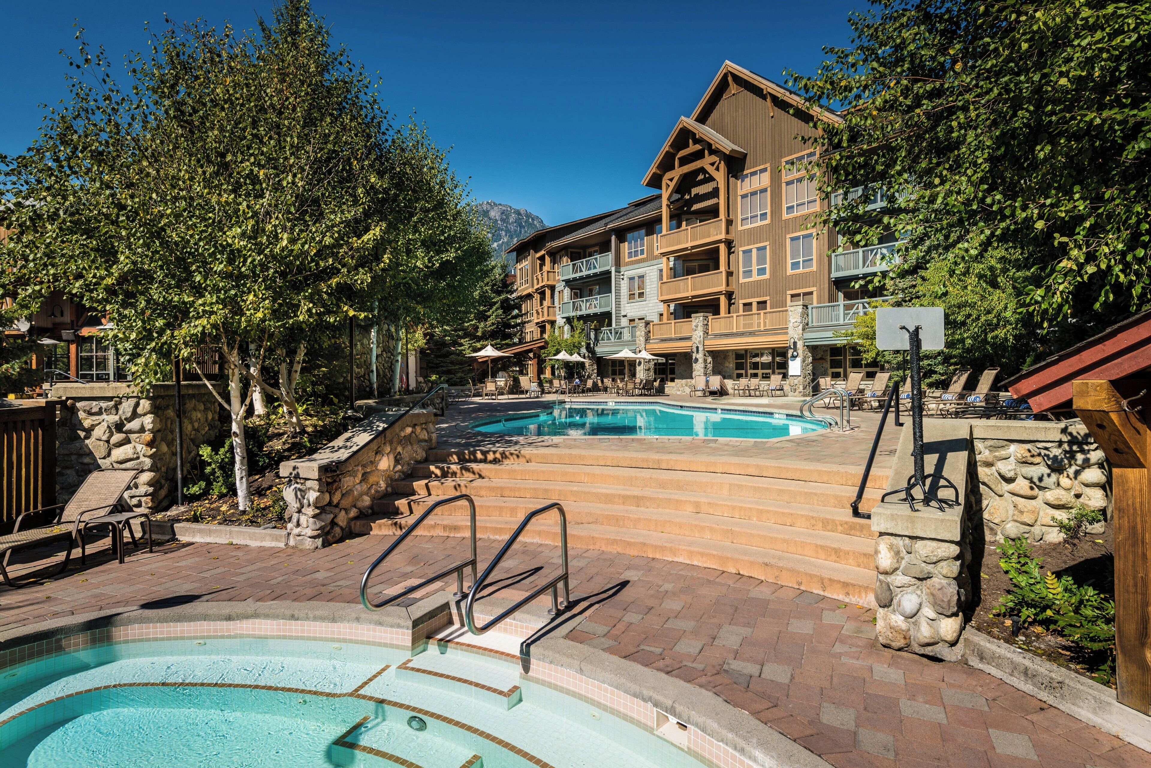 A resort with multiple swimming pools, stone steps, and a wooden building with balconies.